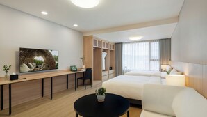 Una habitación de hotel moderna con una cama, un escritorio, una silla, un televisor y una pequeña mesa con una planta.