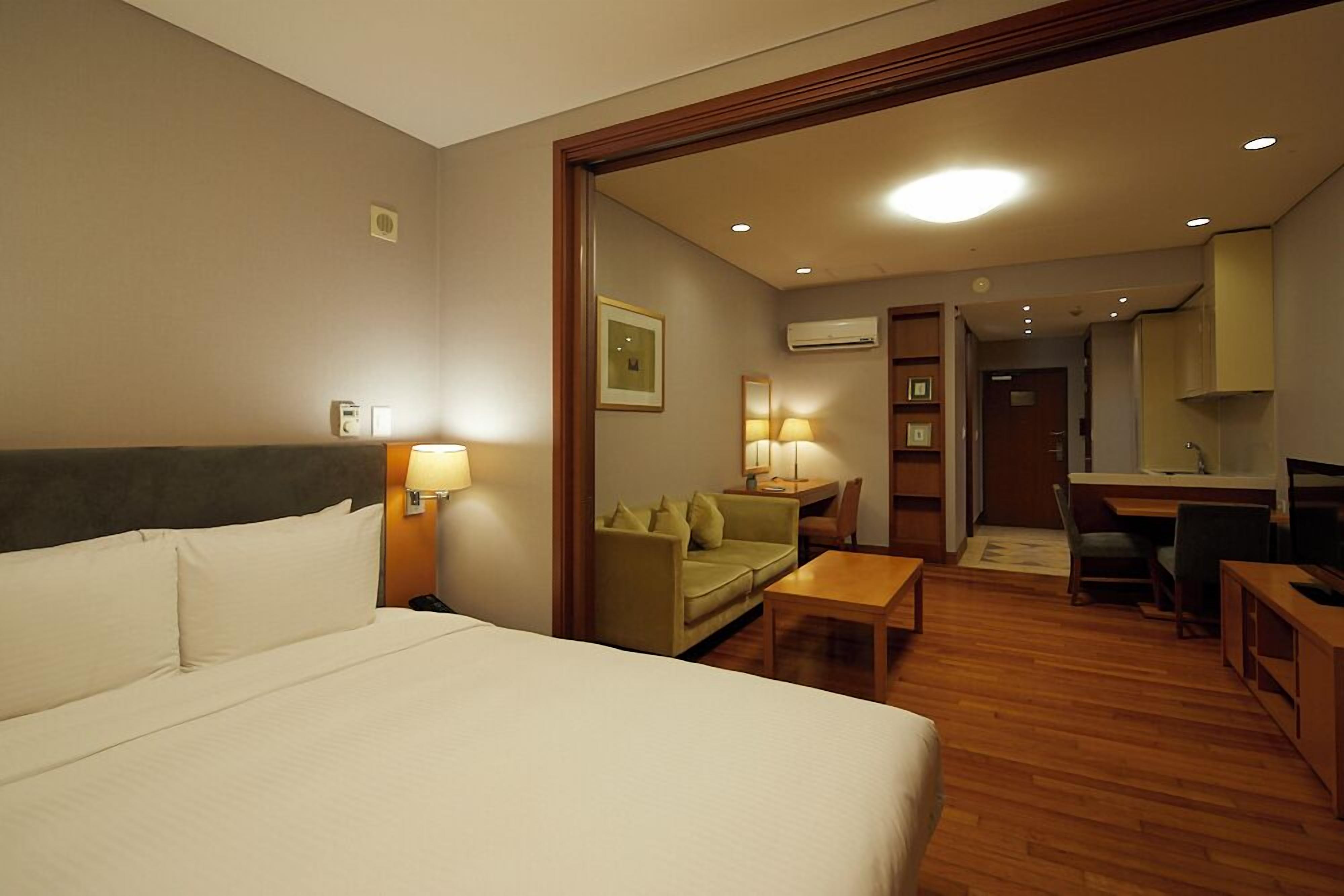 A hotel room with a bed, a desk, a sofa, and a dining table.