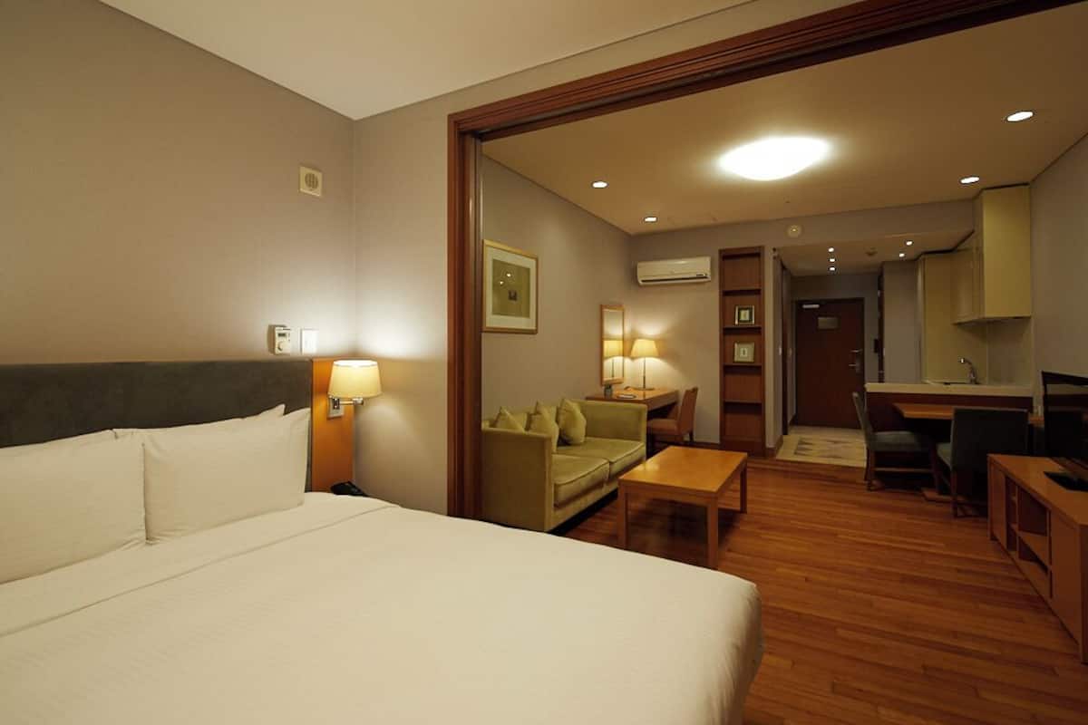 A hotel room with a bed, a desk, a sofa, and a dining table.