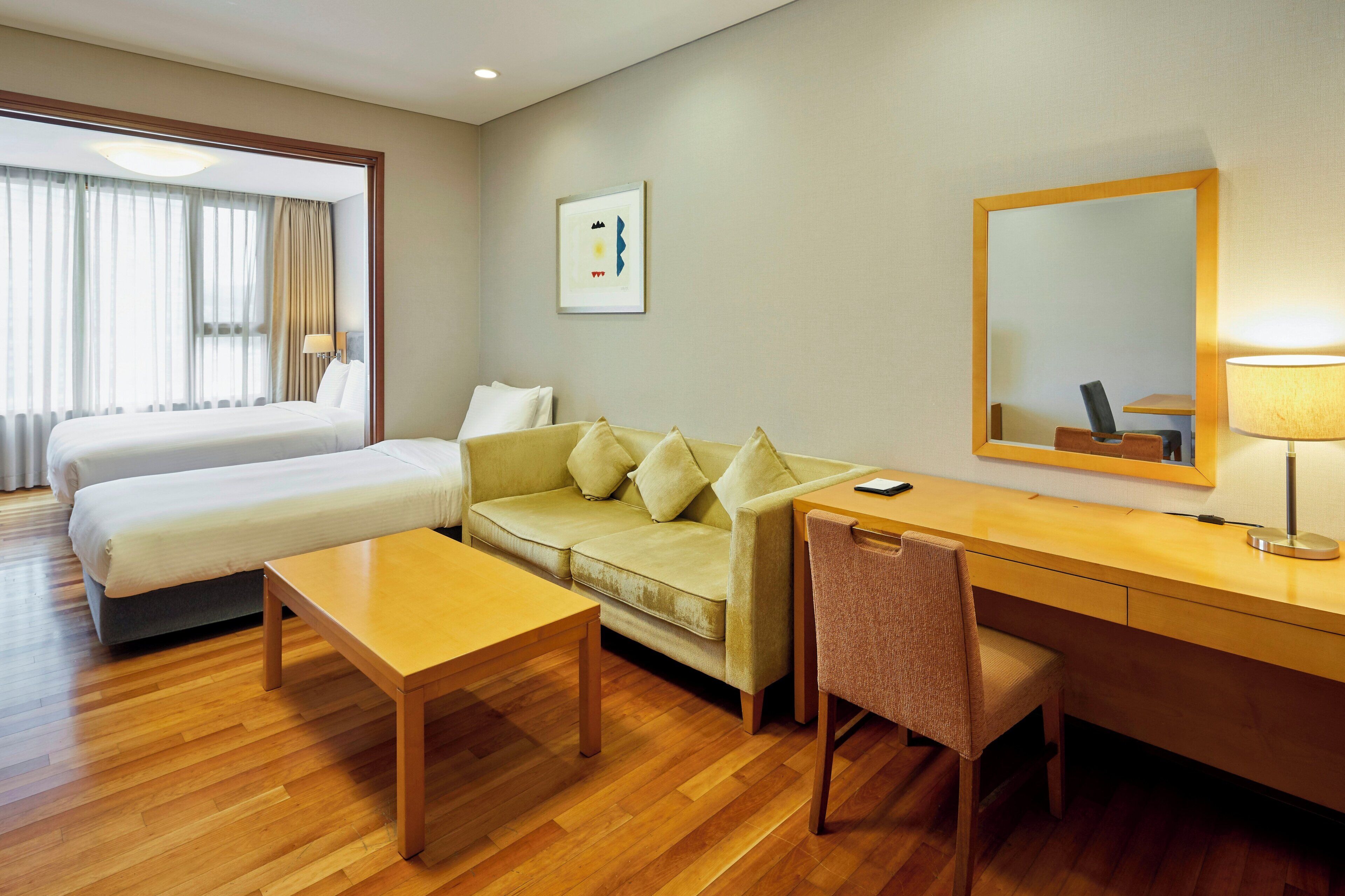 A hotel room with a bed, a sofa, a desk, and a chair.