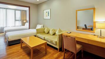A hotel room with a bed, a sofa, a desk, and a chair.
