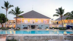 A resort with a swimming pool, a covered outdoor area, and a two-story building with a tiled roof. - Tortuga Bay Hotel (Punta Cana)