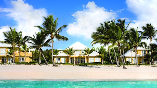 A beachfront hotel with multiple yellow buildings, palm trees, and a clear blue sky. - Tortuga Bay Hotel (Punta Cana)
