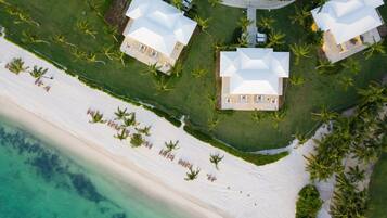 An aerial view of a resort with two large buildings, a beachfront, and palm trees.