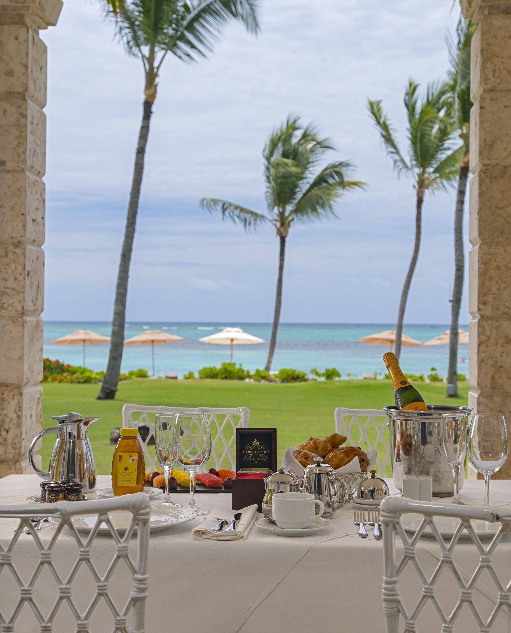 A table set for breakfast with a view of the ocean and palm trees.