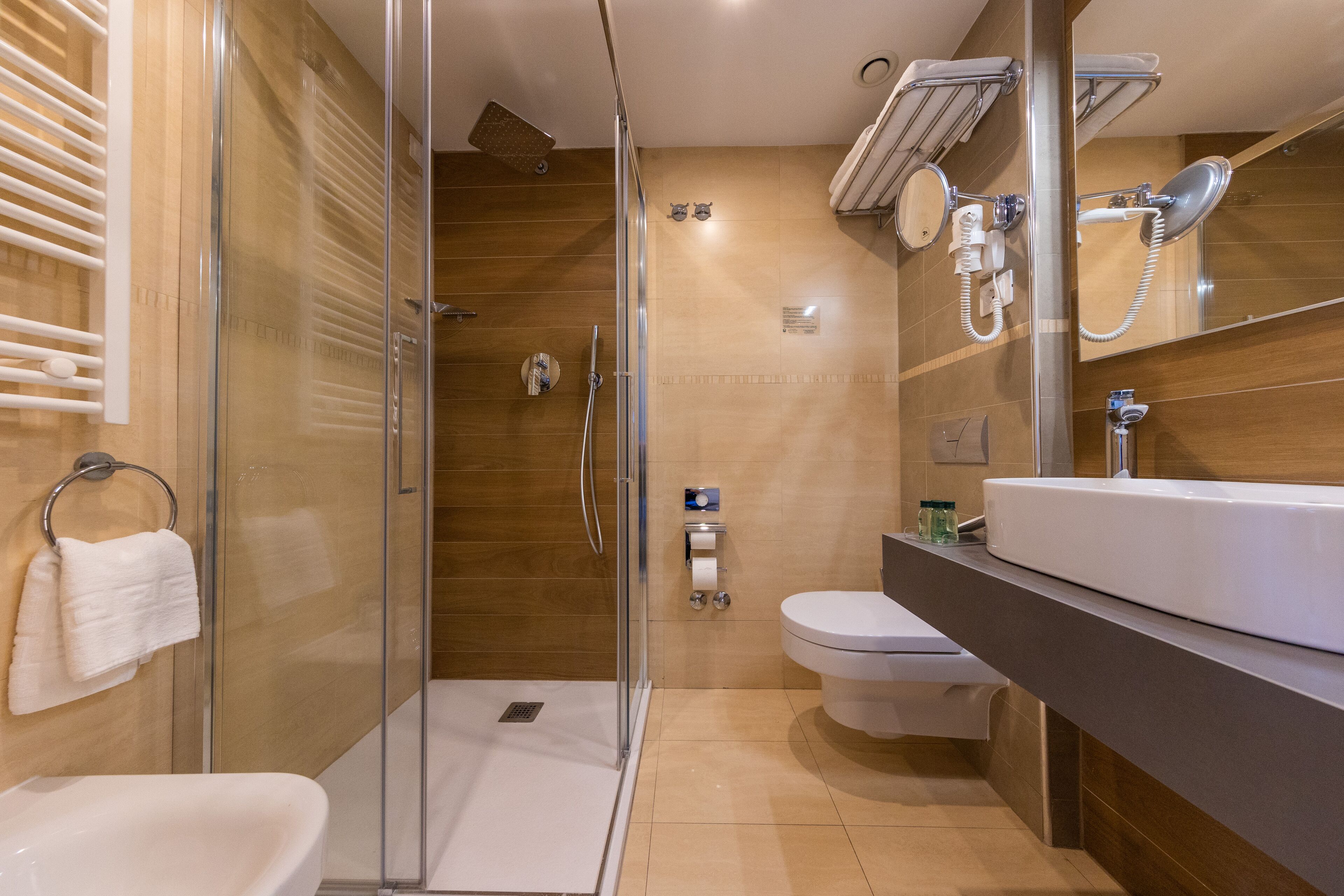 A modern bathroom with a glass-enclosed shower, a toilet, and a sink.