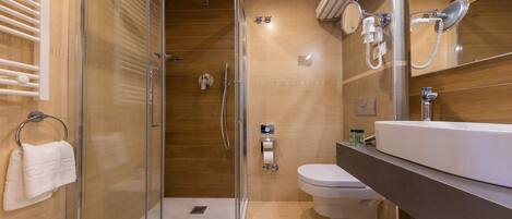 A modern bathroom with a glass-enclosed shower, a toilet, and a sink.