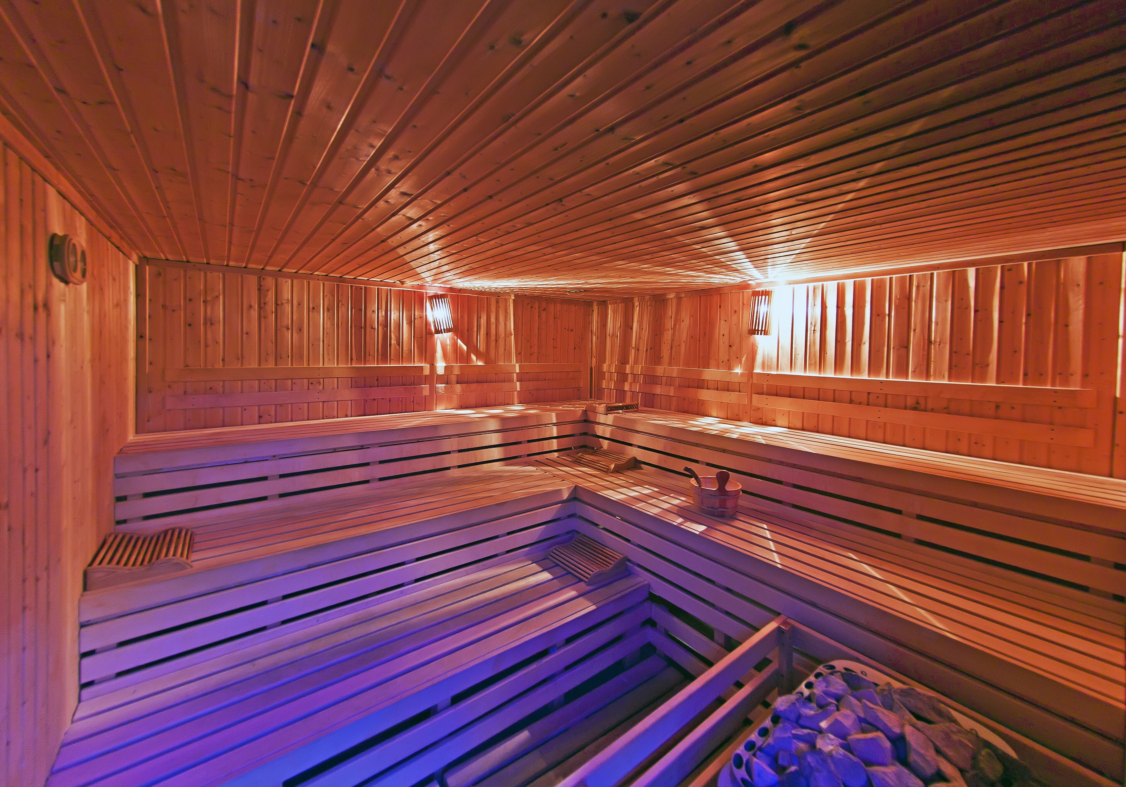 Una sauna con bancos de madera y piso inclinado, presumiblemente diseñada para la relajación y la terapia con vapor.