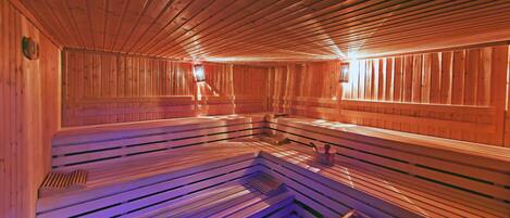 Una sauna con bancos de madera y piso inclinado, presumiblemente diseñada para la relajación y la terapia con vapor.