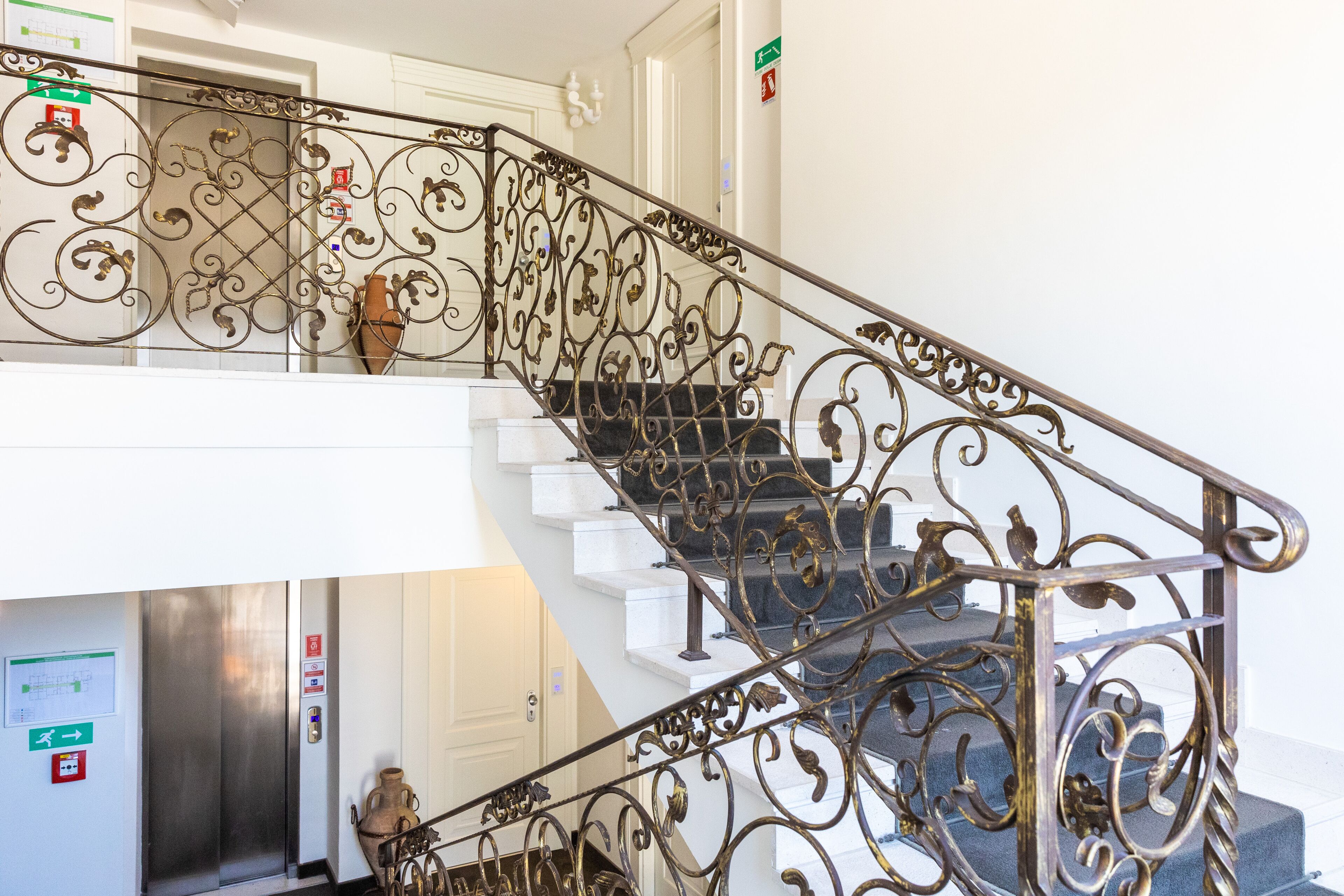 A staircase with ornate metal railings and a vase on the landing.
