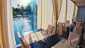 A dining area with a view of a pool and palm trees. - Grand Hotel Park (Dubrovnik)