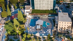 An aerial view of a hotel with a rooftop pool, surrounded by landscaped gardens and palm trees. - Grand Hotel Park (Dubrovnik)