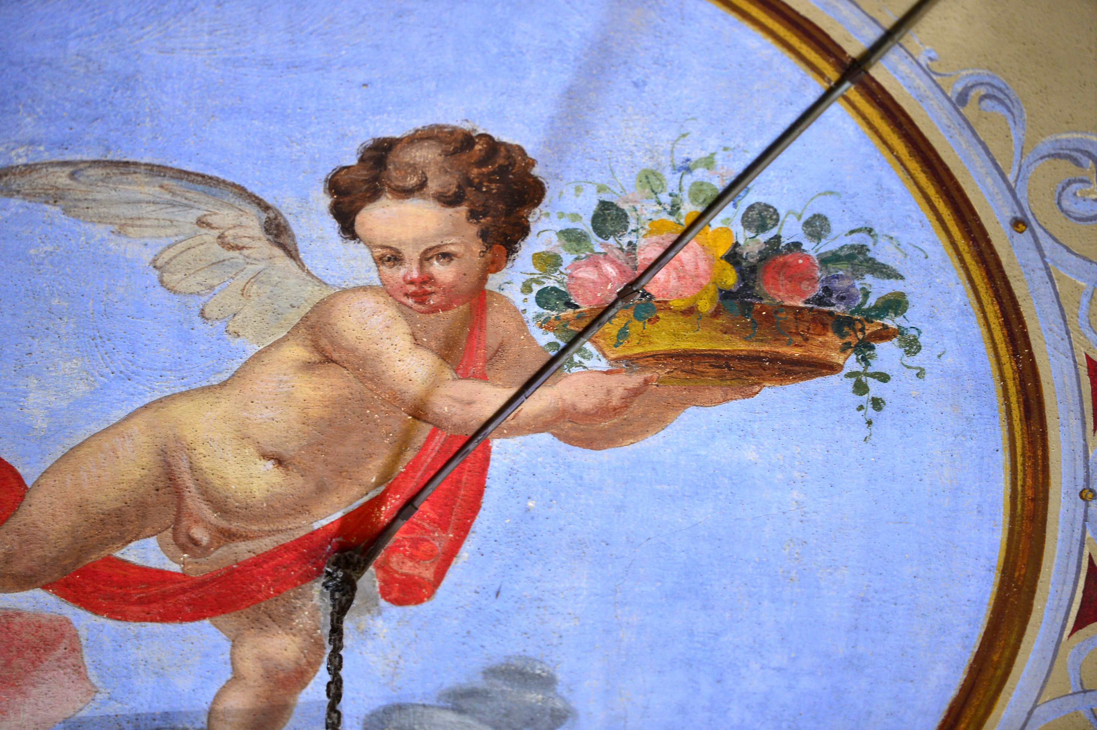 A fresco of a cherub holding a basket of fruit and flowers.