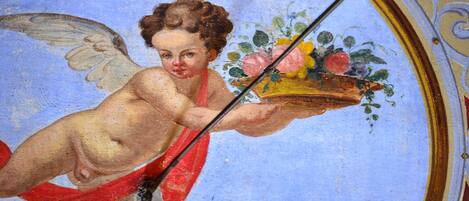 A fresco of a cherub holding a basket of fruit and flowers.