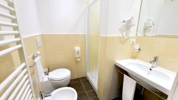 Ein kleines Badezimmer mit Toilette, Bidet, Waschbecken und Handtuchhalter.