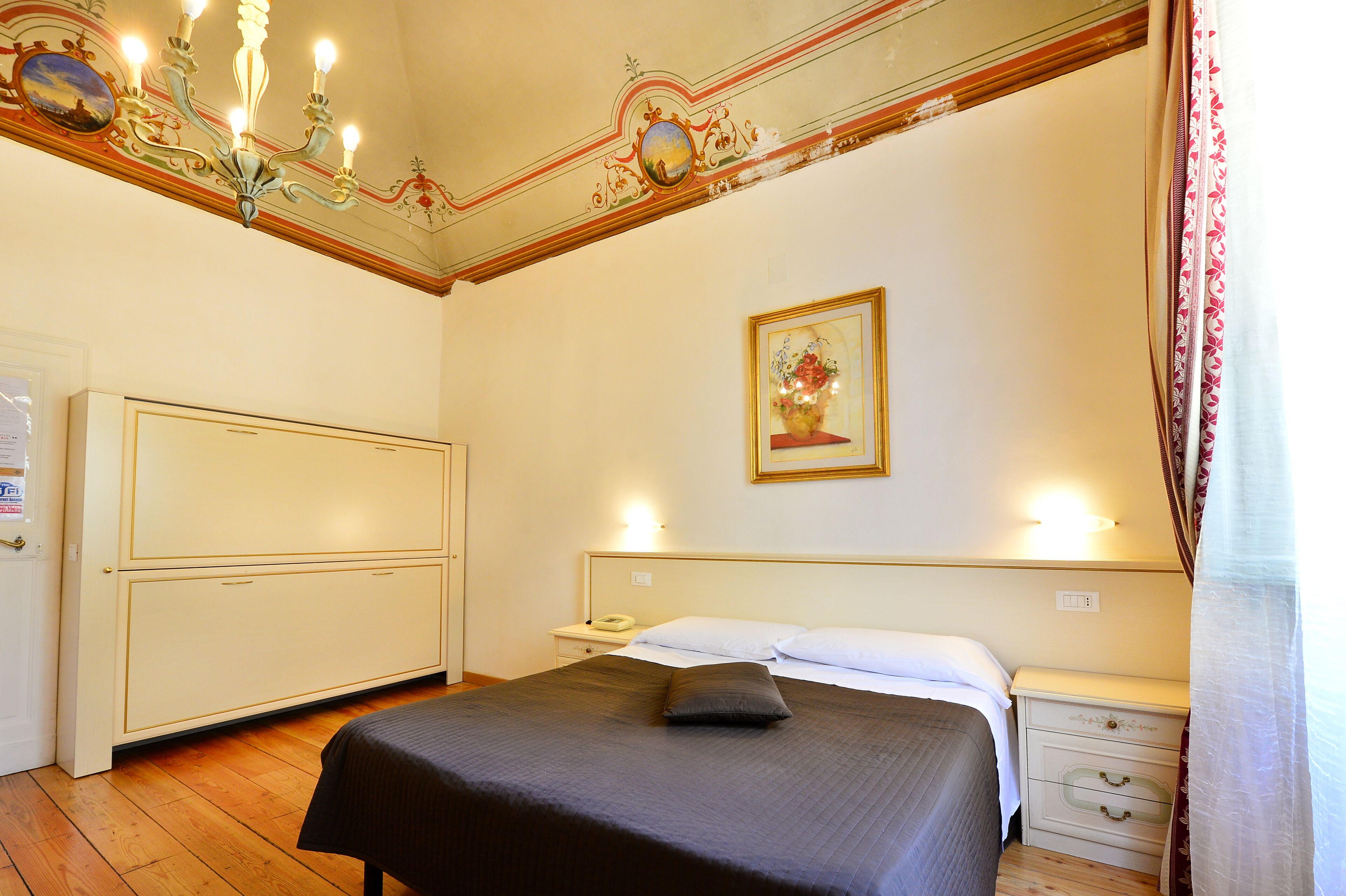 Un dormitorio con cama, mesita de noche y decoración en el techo.