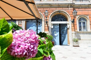 A building facade with arched windows and a door, surrounded by potted plants and a tiled pavement. - Hotel Iris (Perugia)