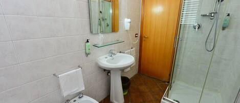 A bathroom with a sink, bidet, and glass-enclosed shower.