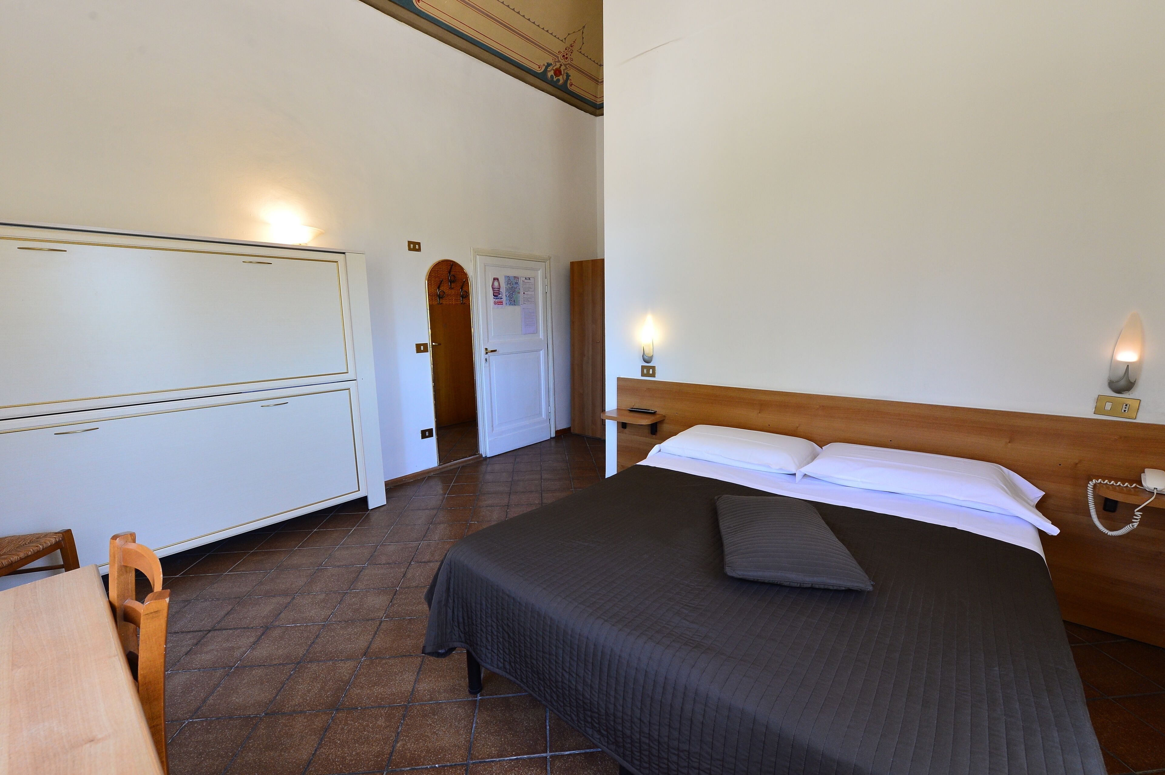 A bedroom with a bed, bedside table, and a wooden headboard.