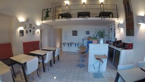 A dining area with tables and chairs, a kitchen area with appliances, and a balcony with railings. - Micalò ArtRooms (Naples)