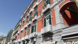 A row of red buildings with balconies, some with plants. - Micalò ArtRooms (Naples)