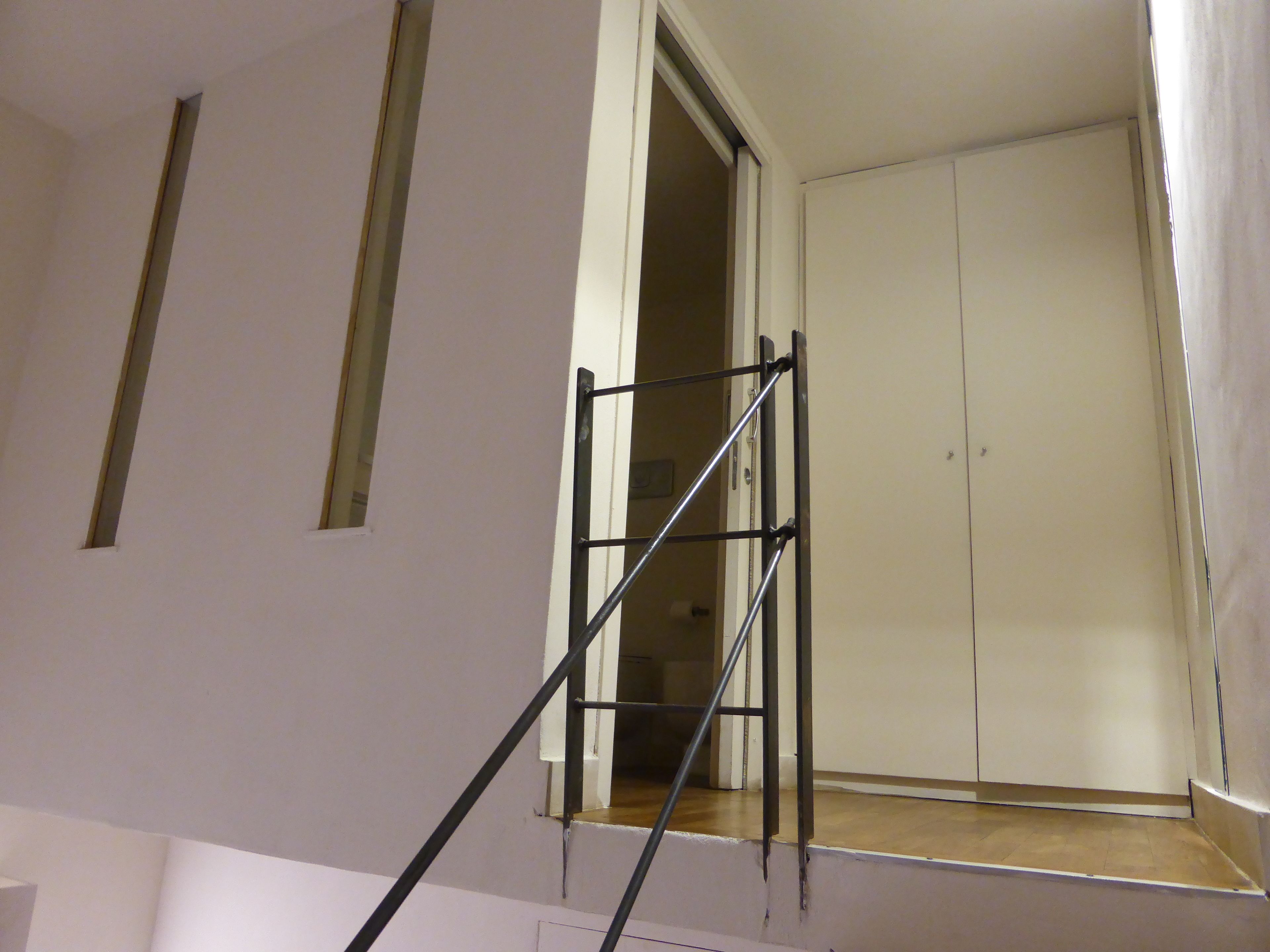 A staircase with a metal handrail leading to a room with a closed door and a window.