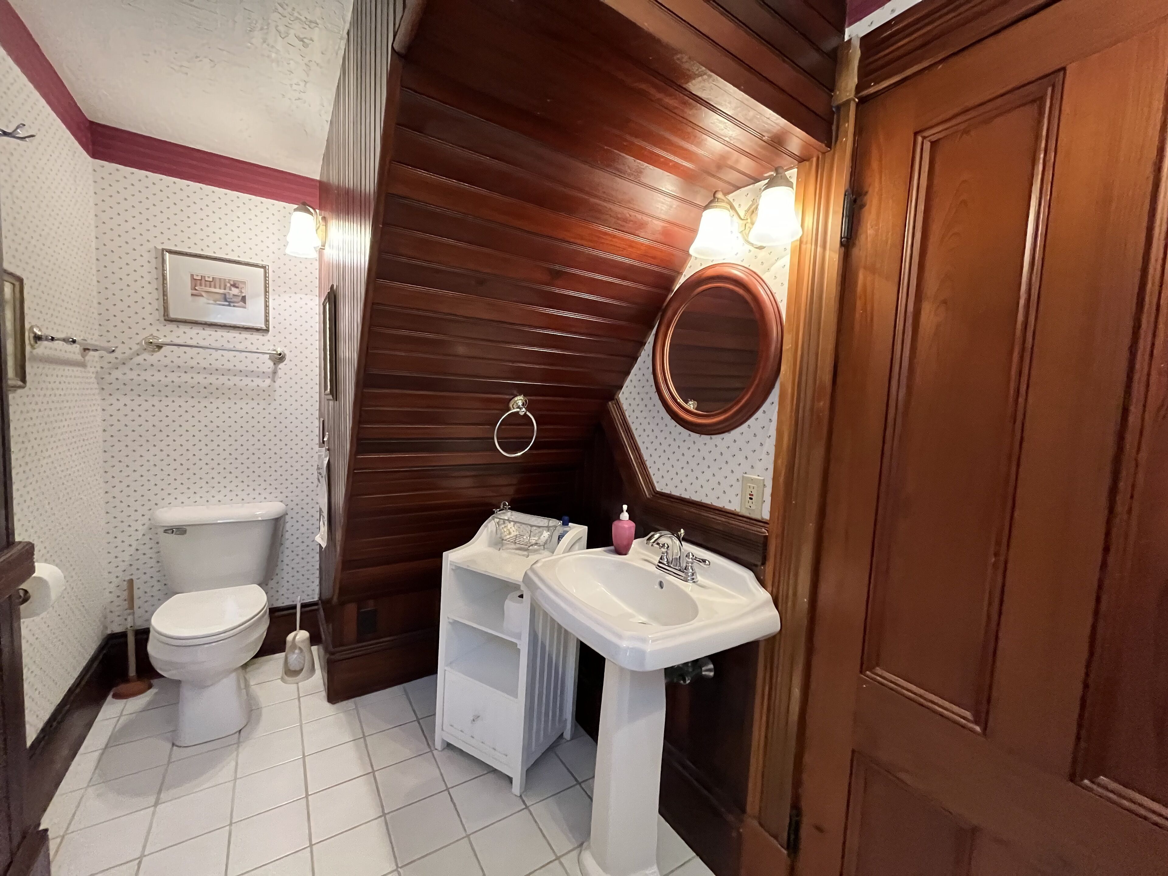 A bathroom with a toilet, sink, and mirror.