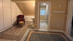 A hallway with a patterned carpet, a red chair, a white closet, and a door leading to a bathroom.