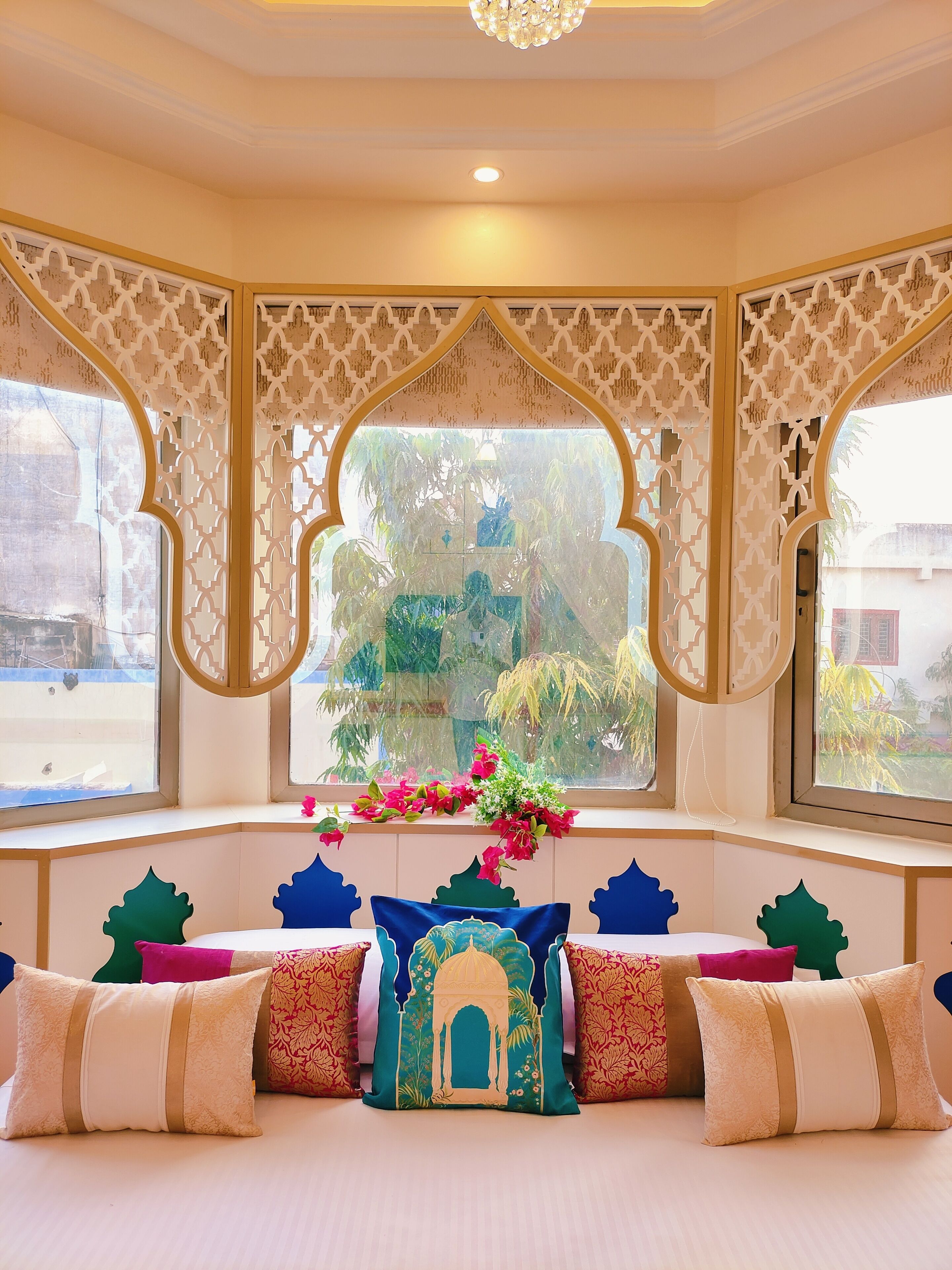 Een kamer met een groot erkerraam, decoratieve witte spijlen en uitzicht op groen.