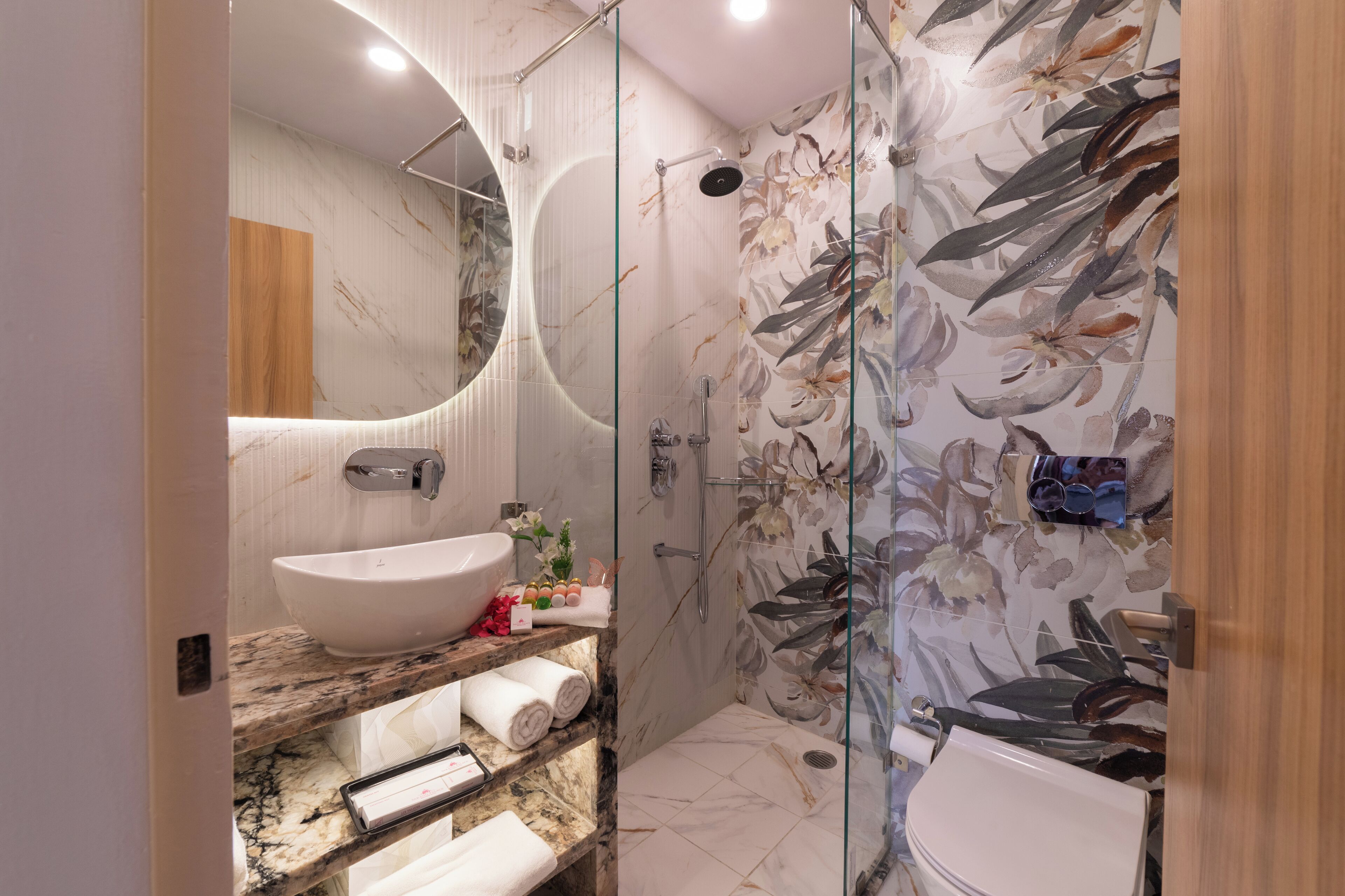 A modern bathroom with a large white sink, a glass-enclosed shower, and a toilet.