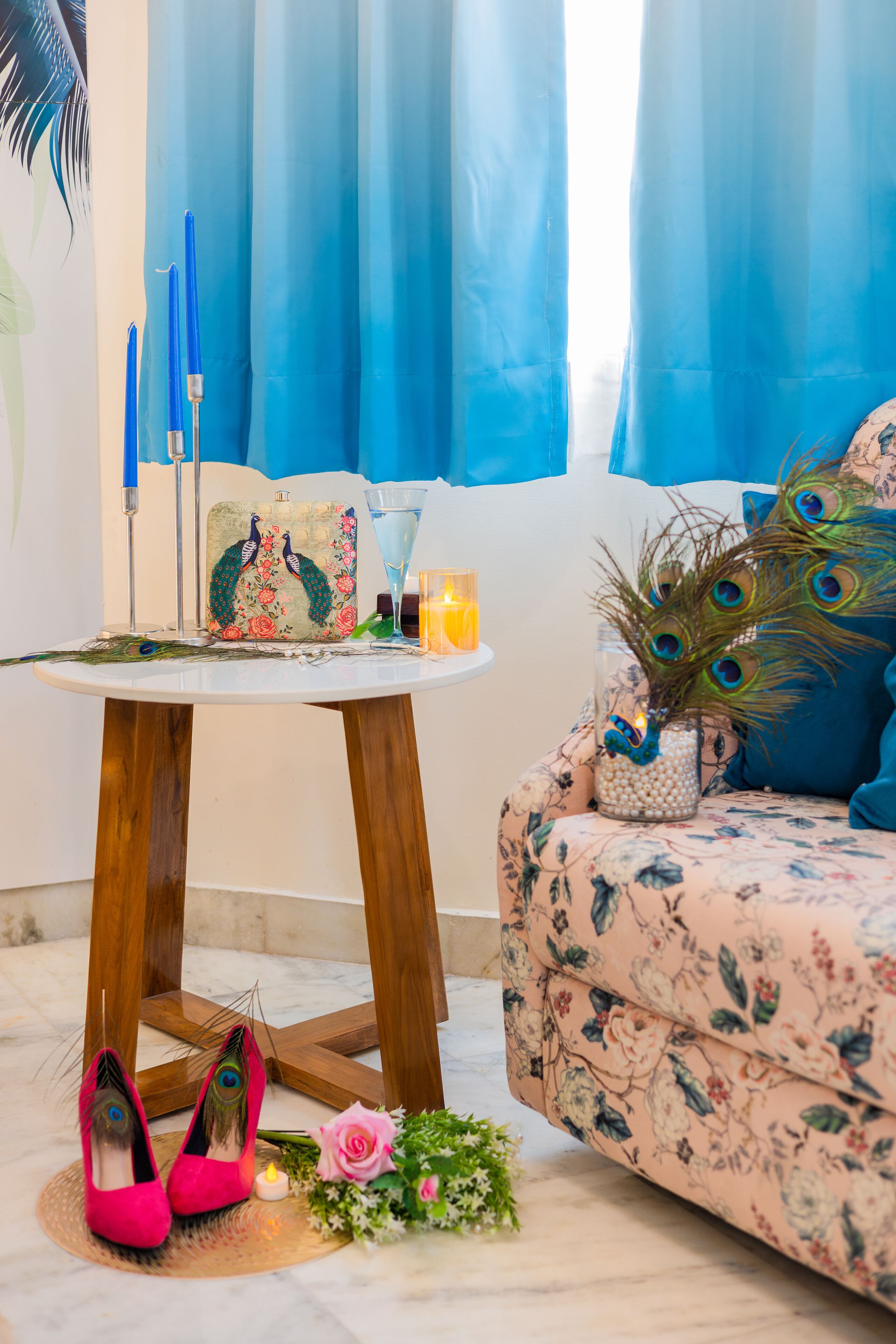 Una habitación con una mesa redonda de madera, un sofá con tapicería floral y una ventana con cortinas azules.