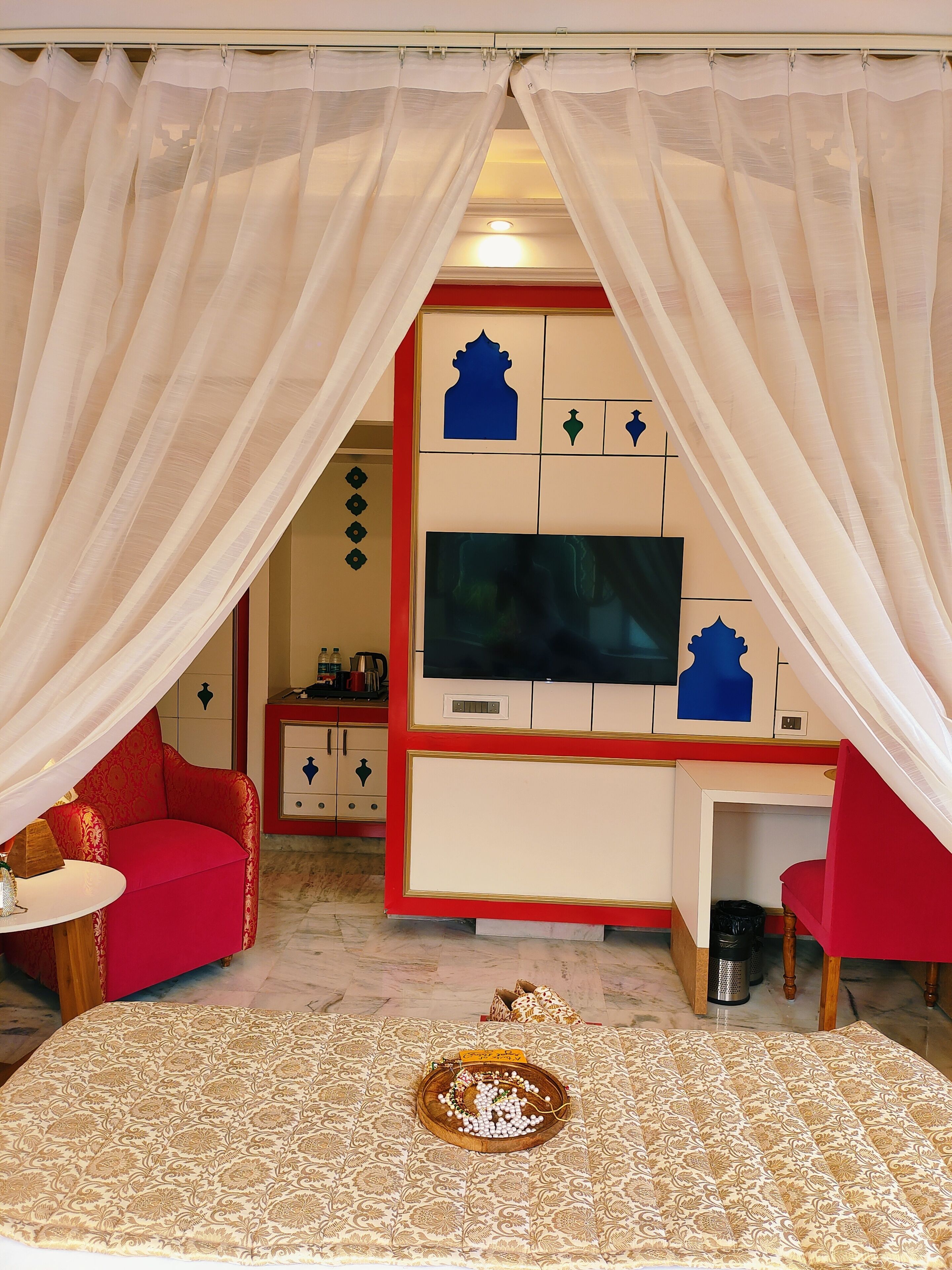 Una habitación con televisión, un sofá rojo, una mesita y una bandeja decorativa con objetos.