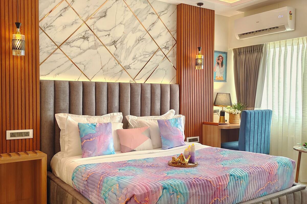 Une chambre moderne dotée d’un grand lit, d’un ventilateur de plafond, d’un mur à motifs de marbre et de panneaux décoratifs en bois.