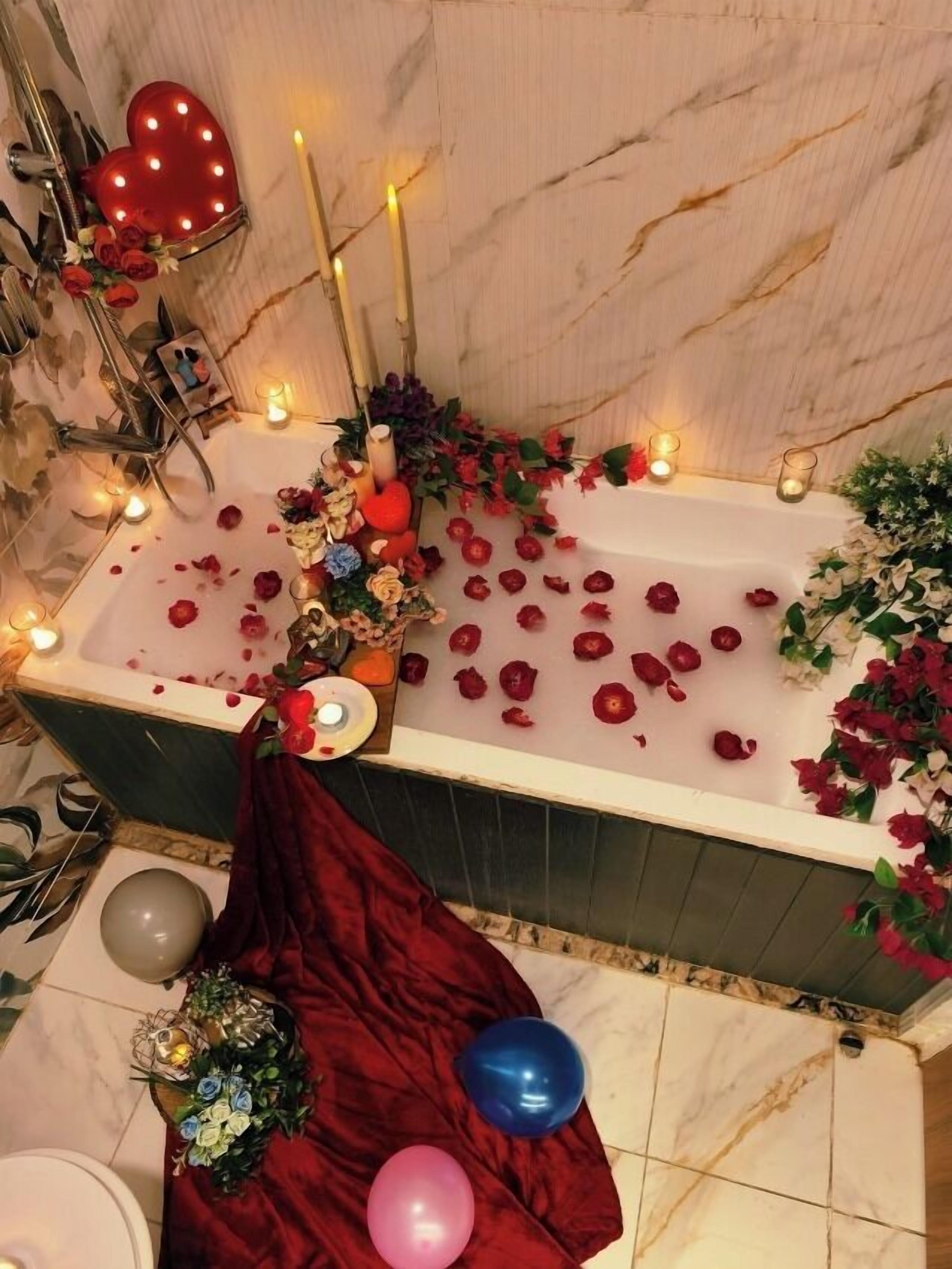 A bathroom with a bathtub, candles, and rose petals.