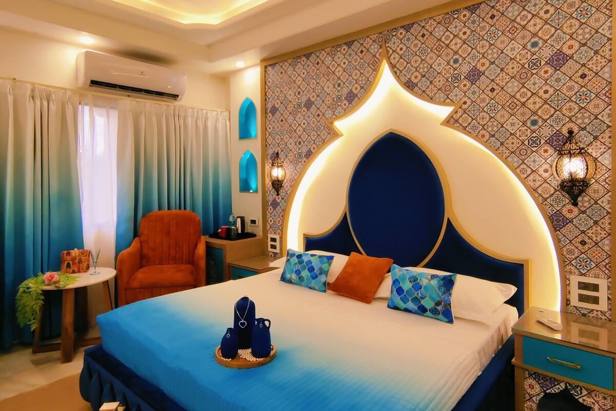 Une chambre moderne avec un grand lit, une chaise, une petite table et un mur décoratif.