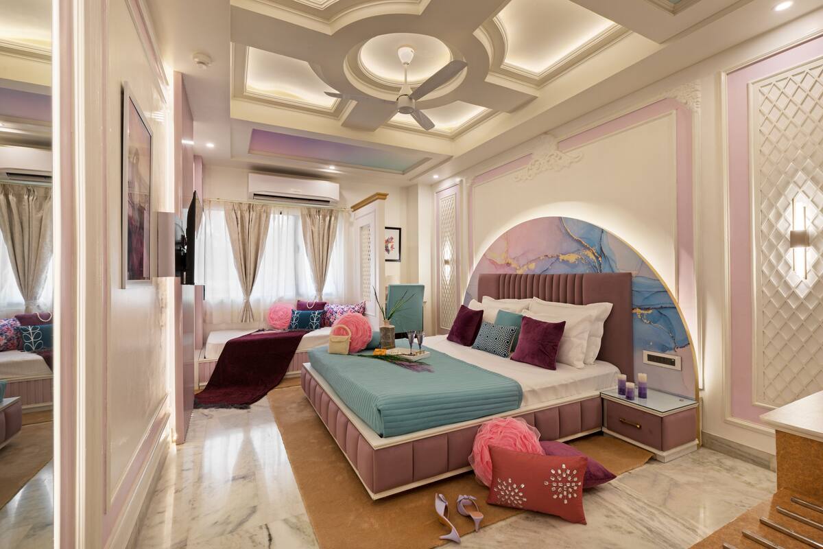 Une chambre à coucher avec un grand lit, des tables de chevet, une coiffeuse et un ventilateur de plafond.