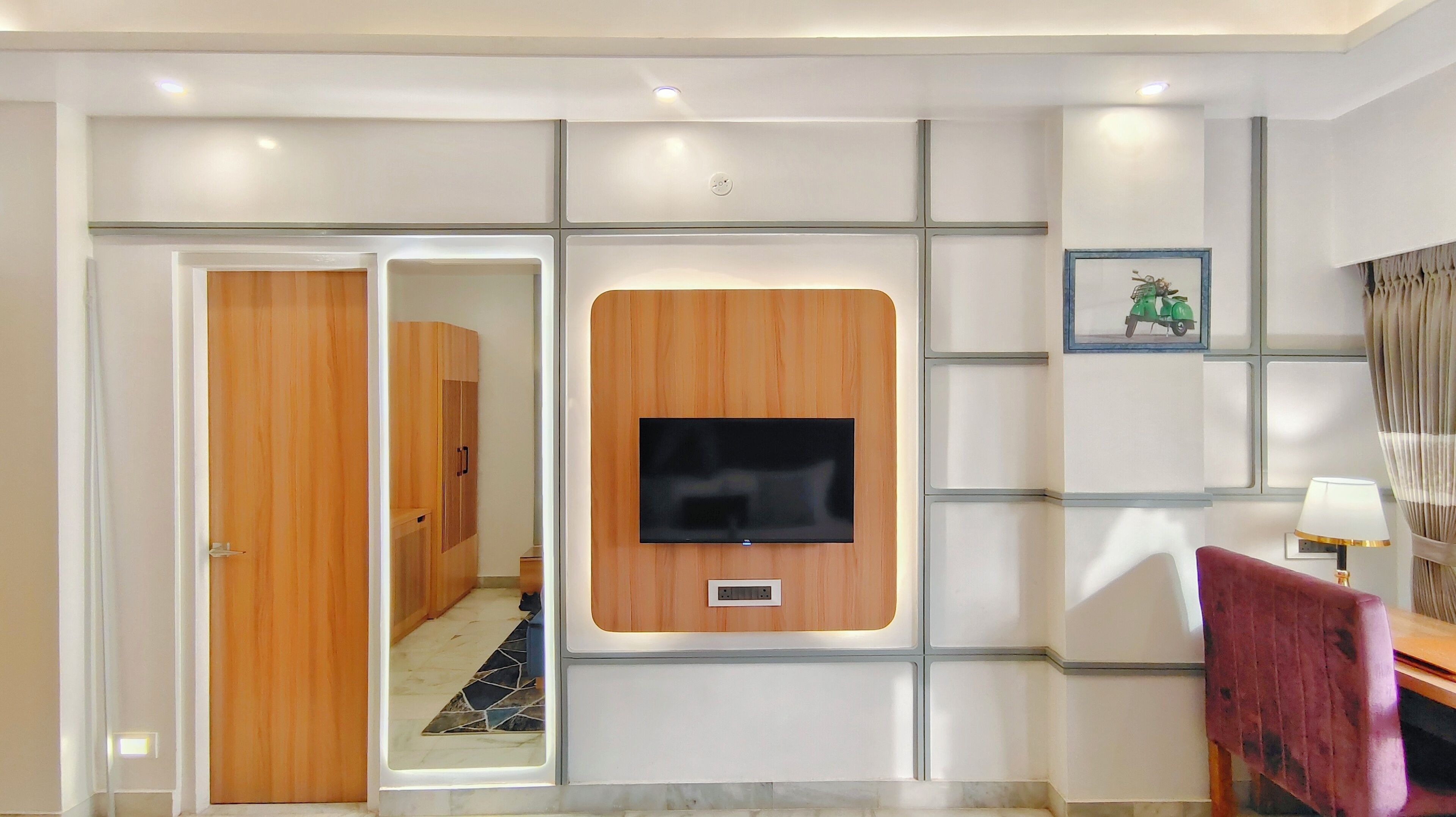 A modern room with a wooden wardrobe, a mounted TV, and a red chair.