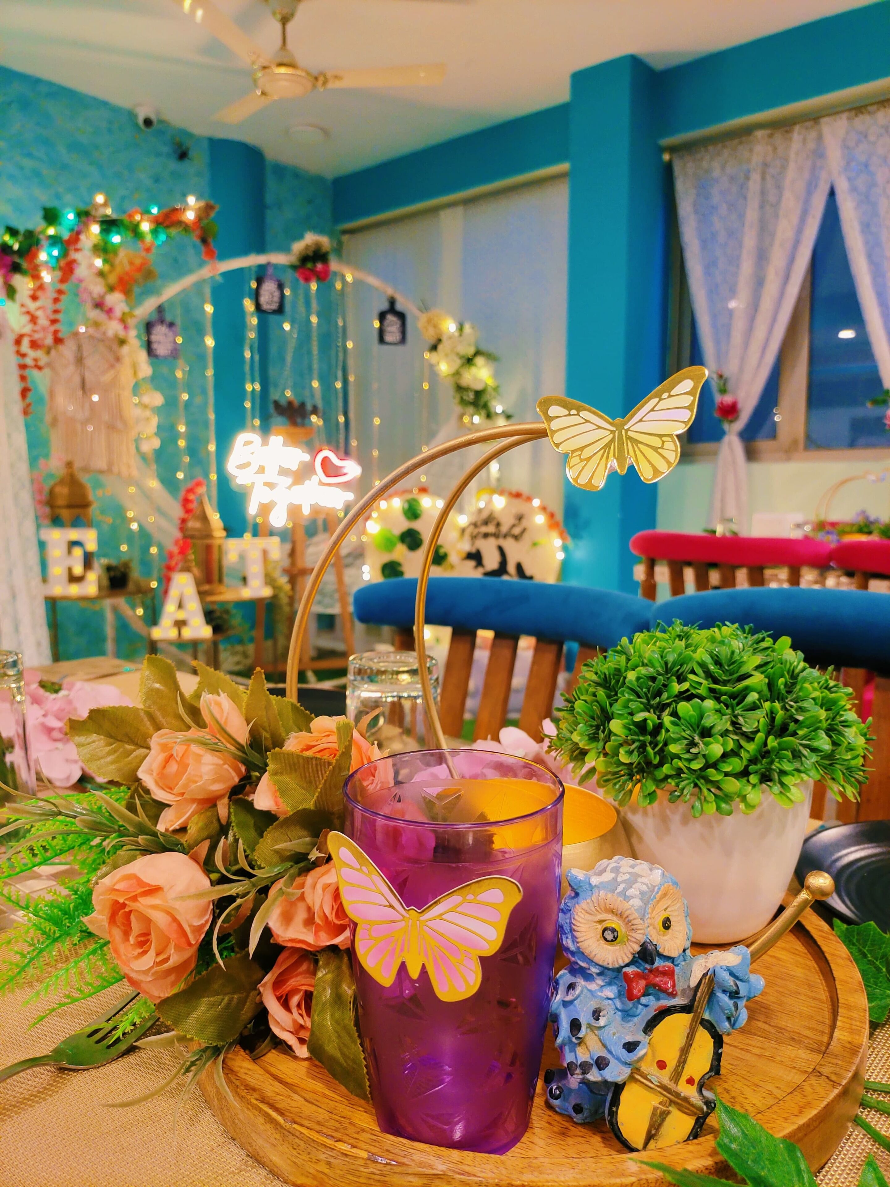 A table with a purple drink, a small potted plant, and decorative items.