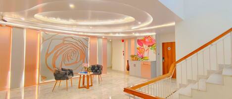 Un vestíbulo moderno con piso de mármol, una escalera y una recepción con un mural floral.