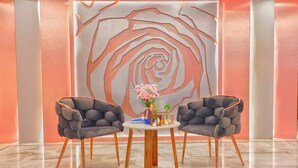 Una habitación moderna con un cuadro de pared floral grande, dos sillones tapizados grises, una mesa redonda de madera y un jarrón con flores.