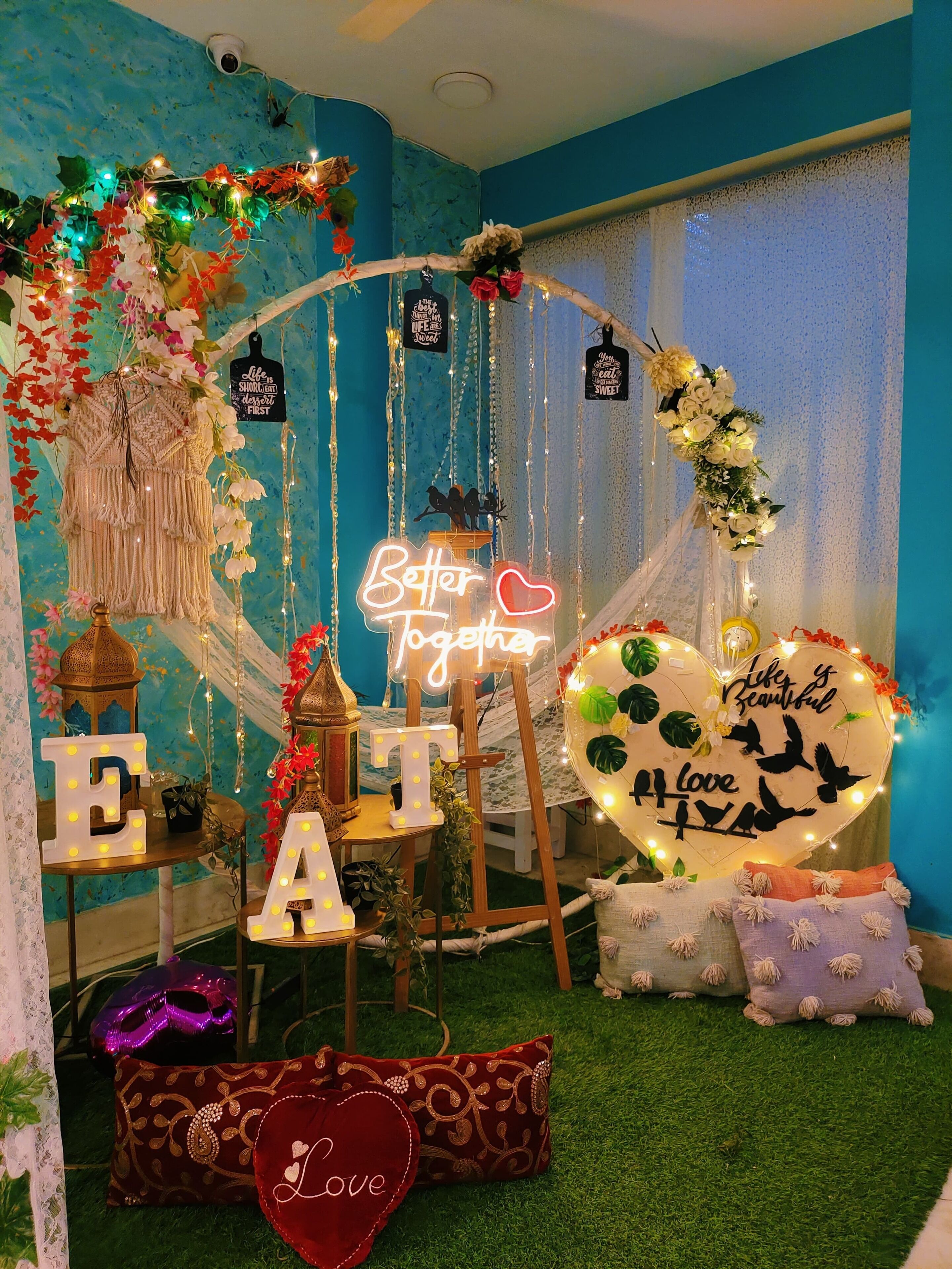 Una habitación decorada con un letrero de neón que dice 'Better Together', un cartel con forma de corazón que dice 'Love' y una pared con un patrón azul texturizado.