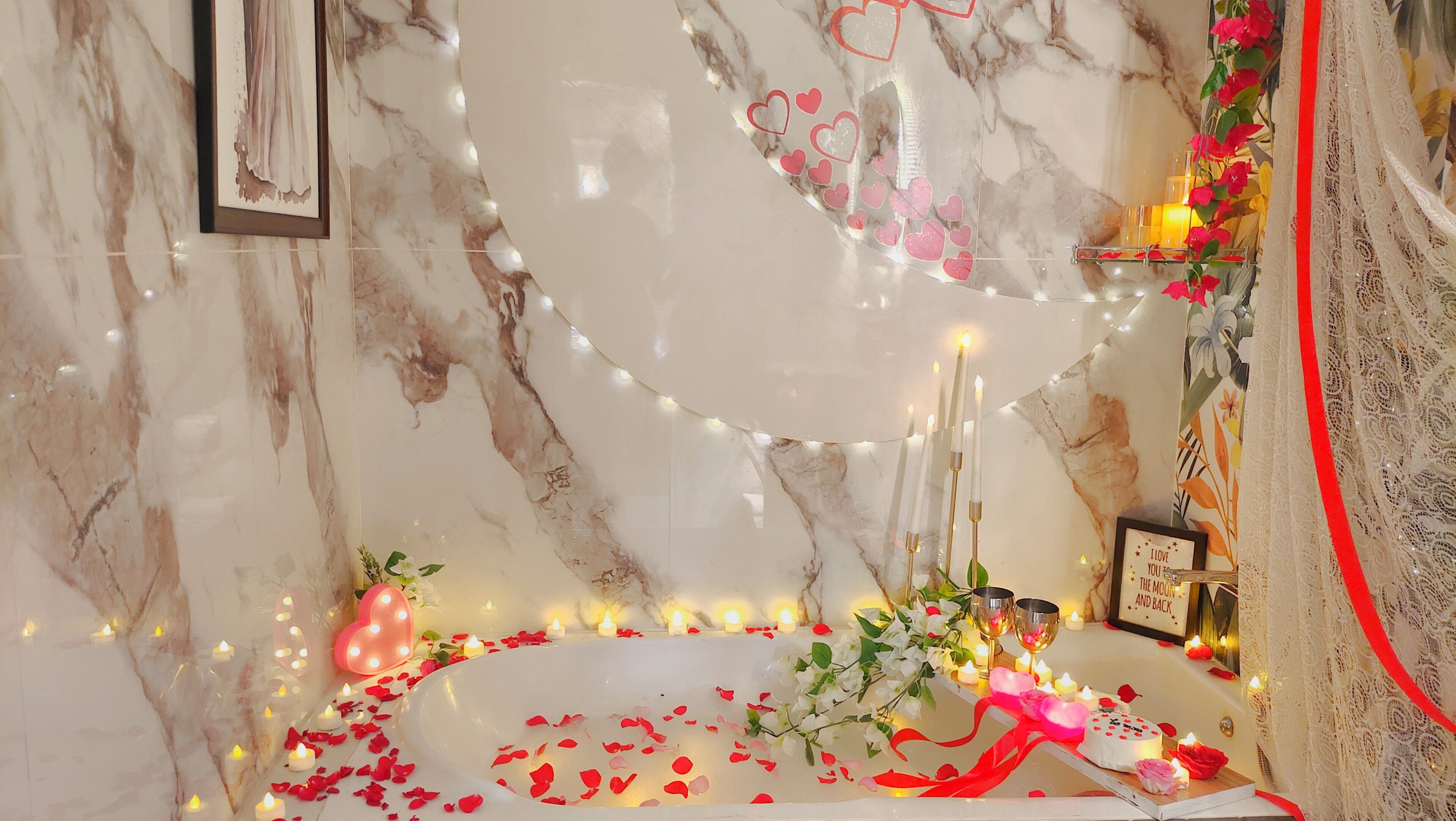A marble bathroom with a bathtub, candles, and decorative flowers.