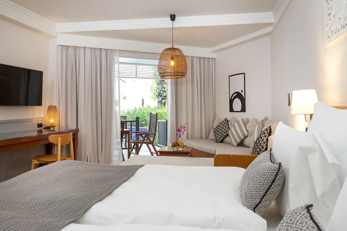 Une chambre d’hôtel équipée d’un lit, d’un bureau, d’une chaise, d’un canapé et d’une télévision.