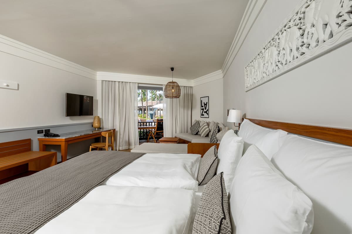 Une chambre d’hôtel avec deux lits, un bureau, une télévision et une vue sur l’extérieur.