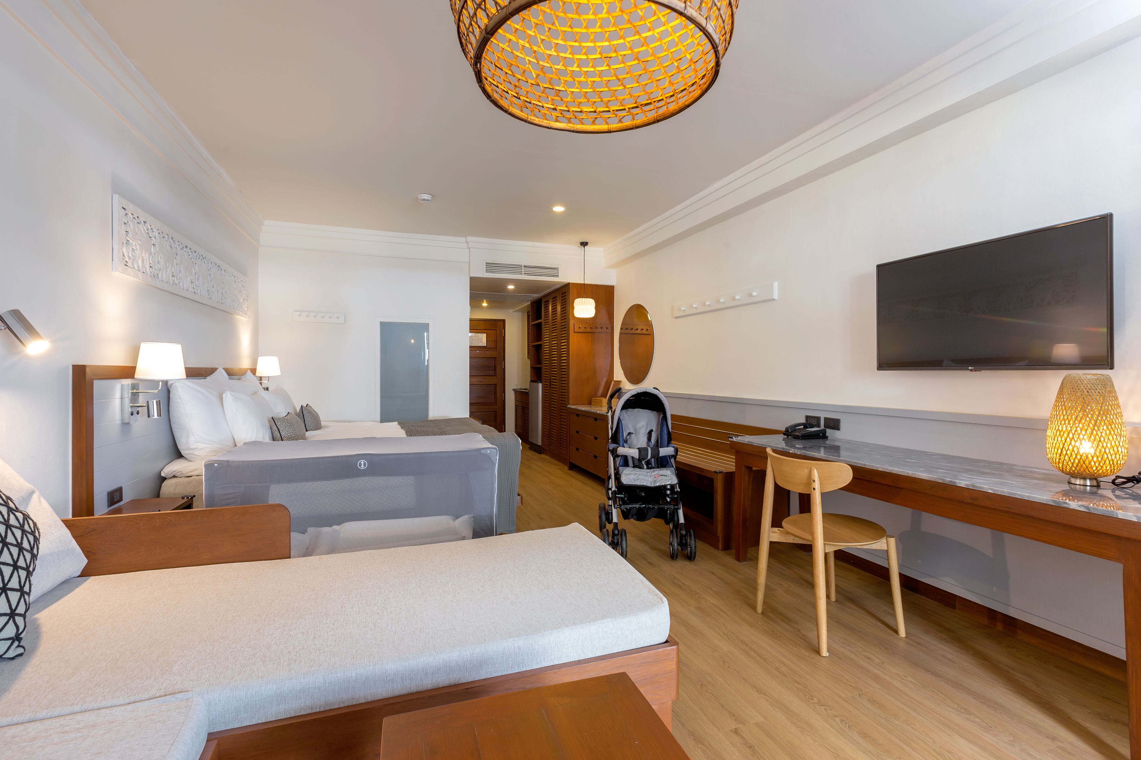 Habitación de hotel con dos camas, un escritorio, una silla, un televisor y una lámpara.