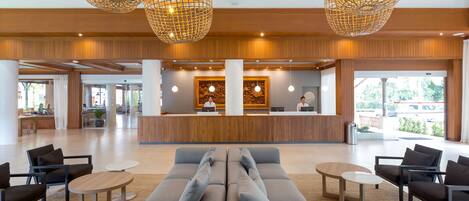 A modern lobby with a reception desk, seating areas, and large windows.