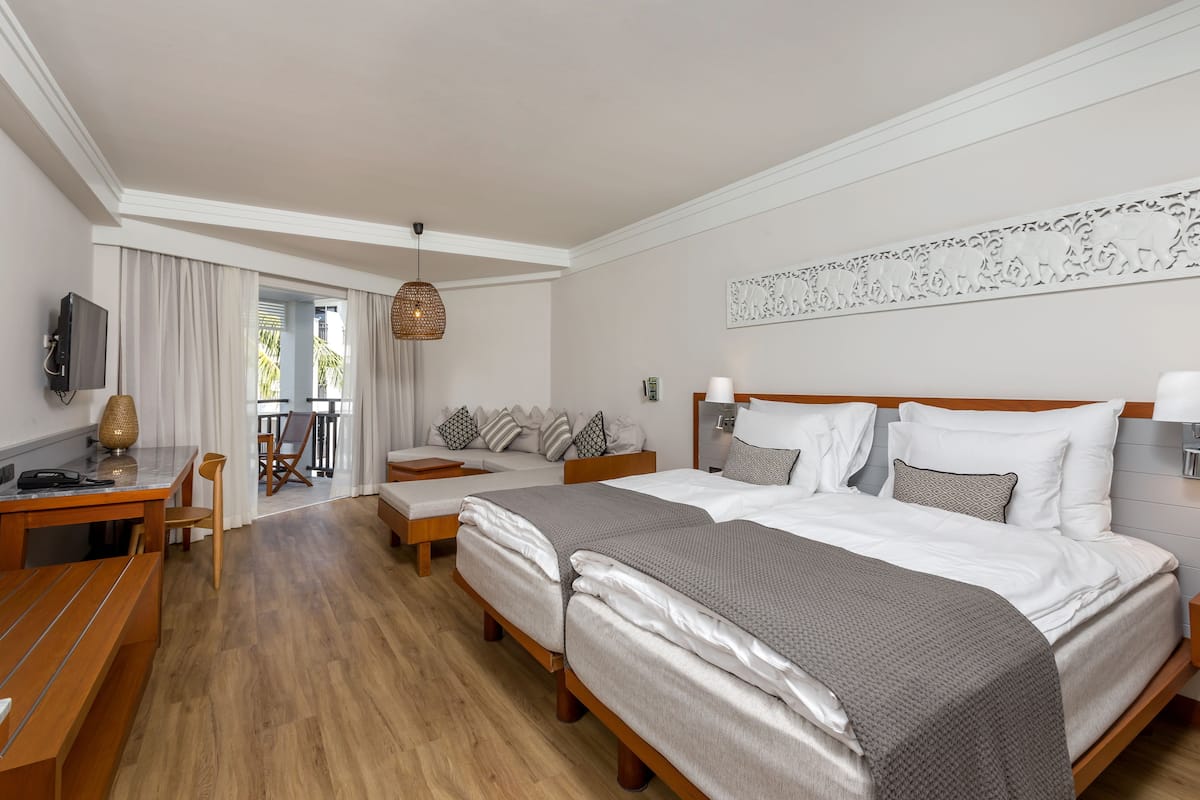 Une chambre d’hôtel avec deux lits, un bureau, une chaise, une télévision et un balcon avec vue.