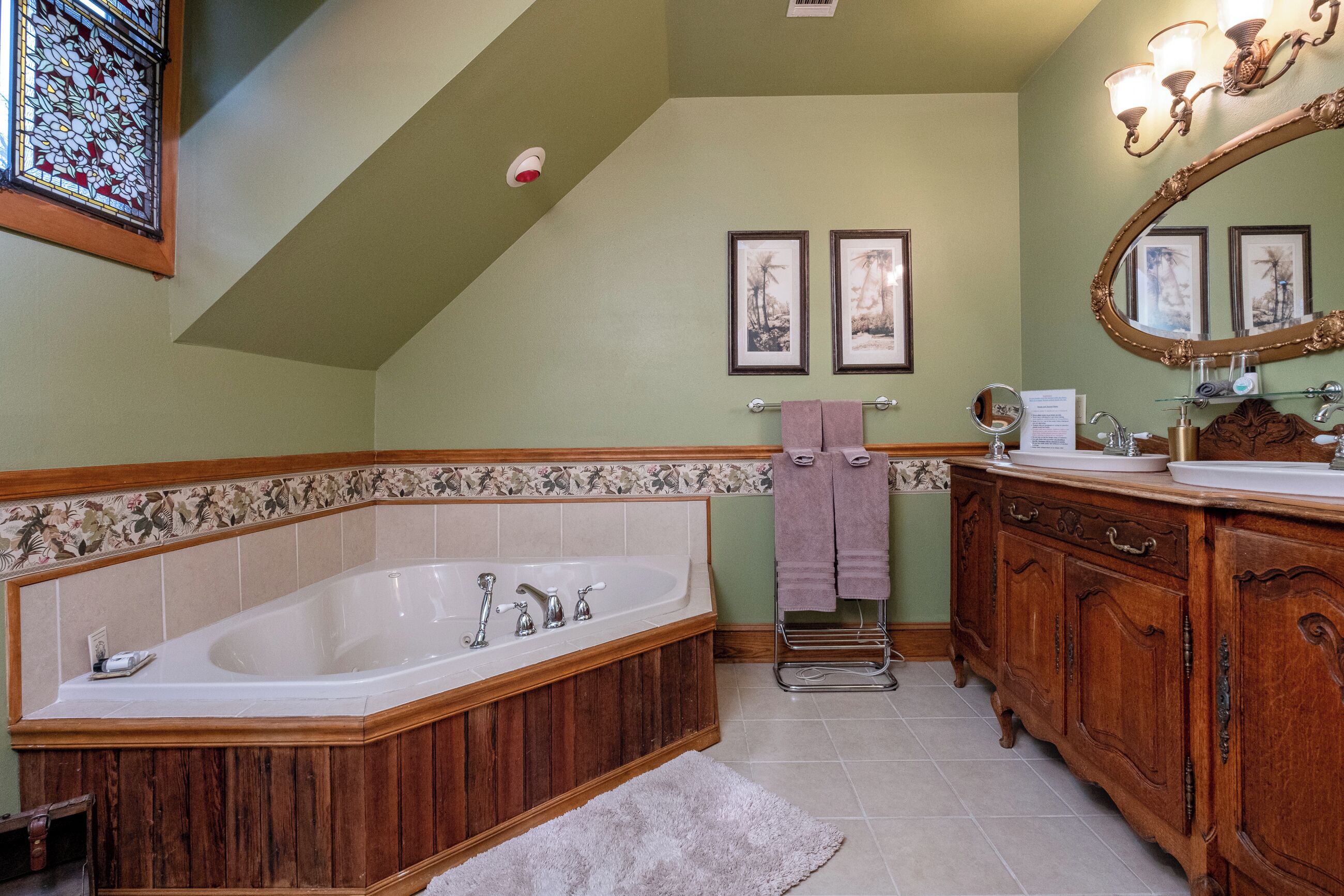 A bathroom with a freestanding bathtub, wooden vanity, and a large mirror.