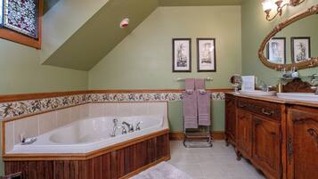 A bathroom with a freestanding bathtub, wooden vanity, and a large mirror.