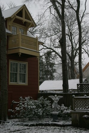 A two-story house with a balcony, surrounded by snow-covered trees and a statue in the yard. - The Empress of Little Rock (Little Rock)
